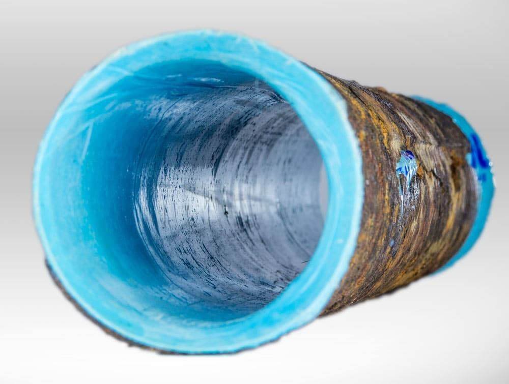 Cross-section of a corroded sewer pipe with a new blue epoxy CIPP liner cured inside