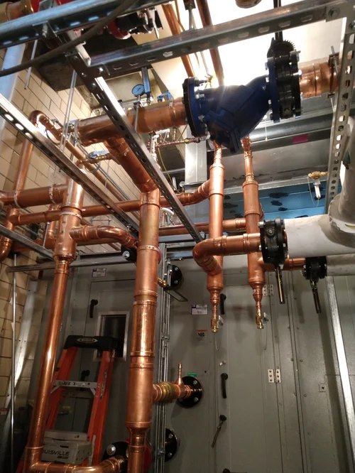Commercial mechanical room with copper piping manifold, valves, and strut-mounted runs