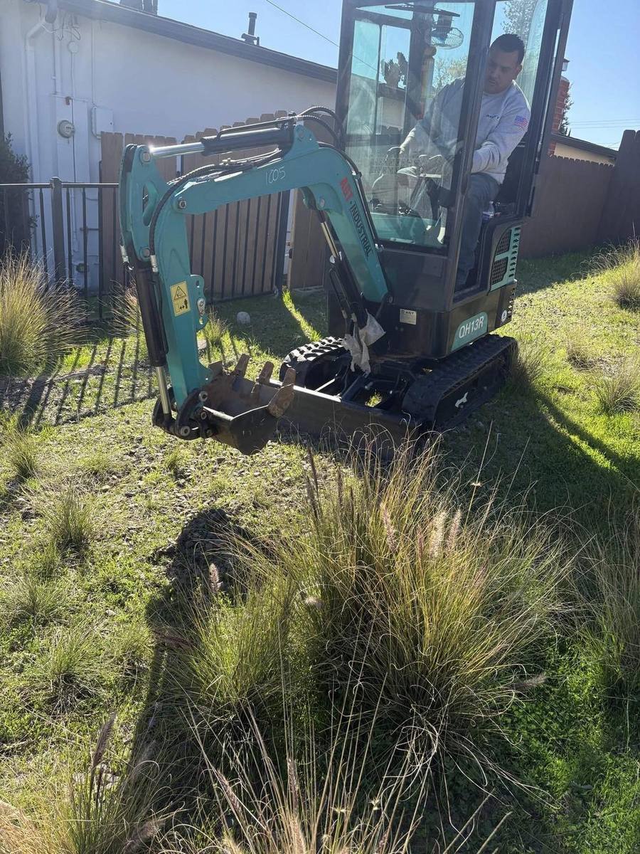 Viper crew operating a compact excavator on a residential sewer dig