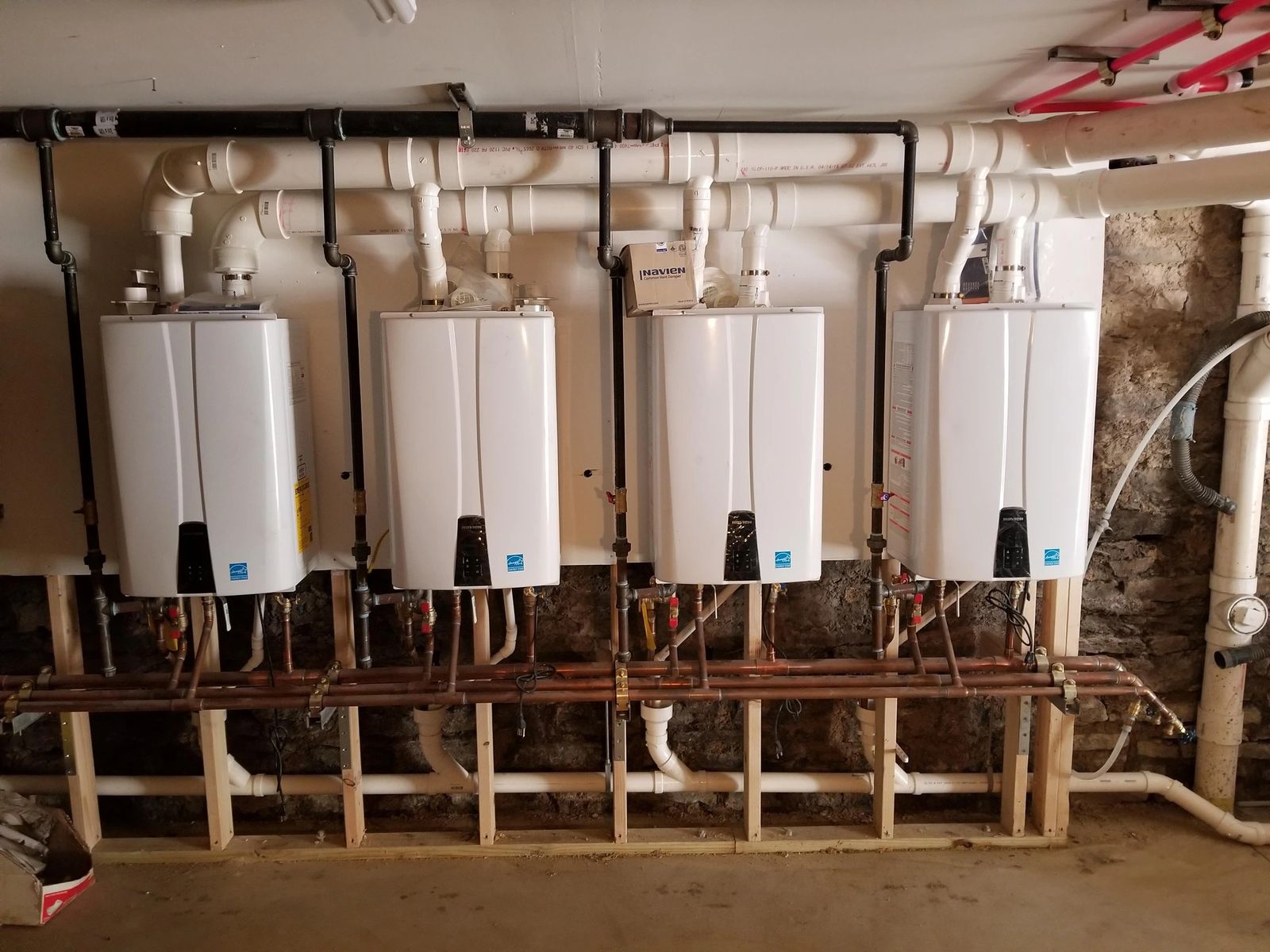Bank of Navien tankless water heaters with common venting and copper manifolds